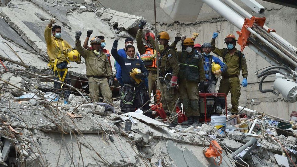 Rescatistas alzan sus puños como una señal para pedir silencio y poder captar el sonido de algún sobreviviente atrapado entre los escombros tras el terremoto en México.