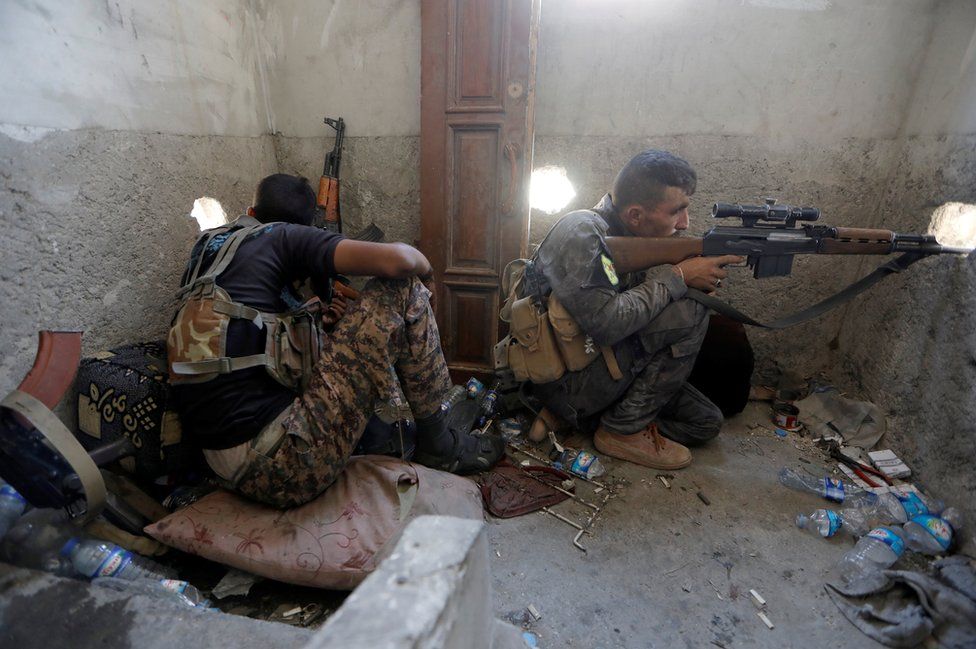 A sniper holds up his weapon.
