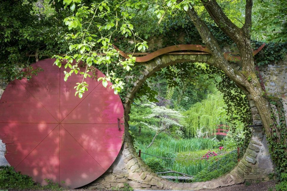 A circular doorway looking onto a green landscaped garden