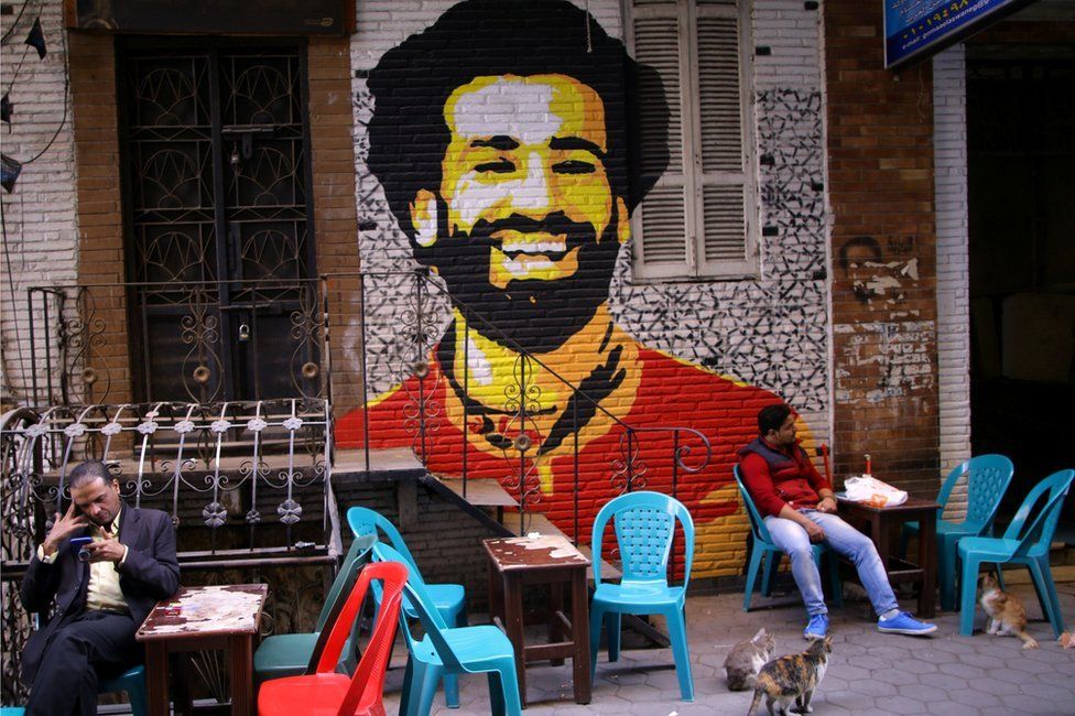 A mural of Egypt and Liverpool football star Mohamed Salah is seen as people sit outside a street coffee shop downtown in the capital of Cairo, Egypt January 16, 2018.