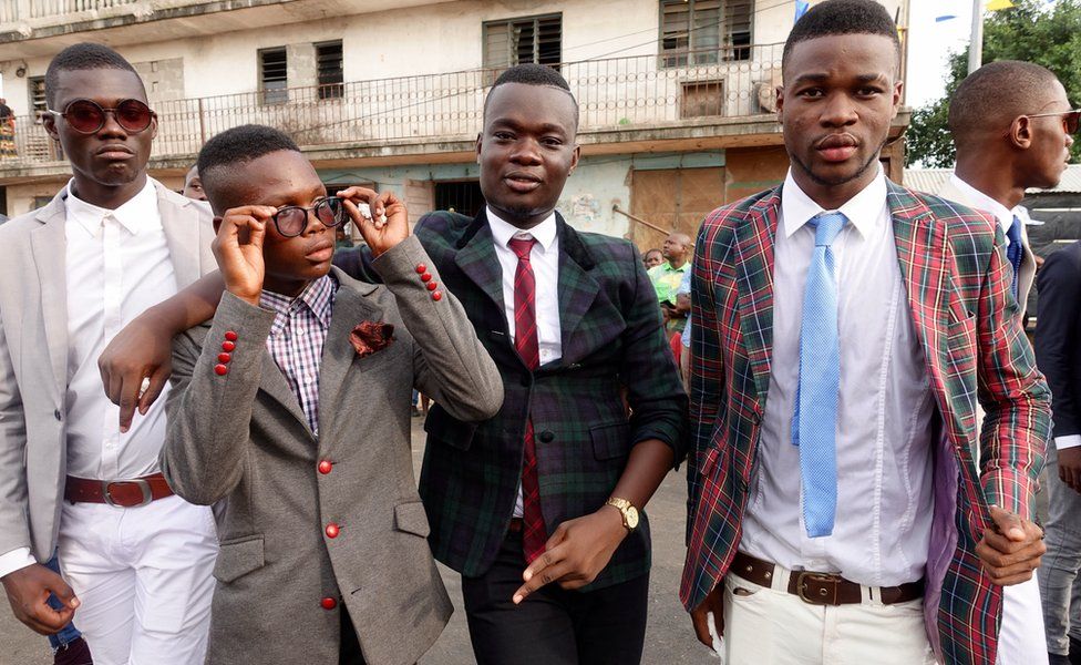 A group of sharply dressed young men in suits and ties pose together