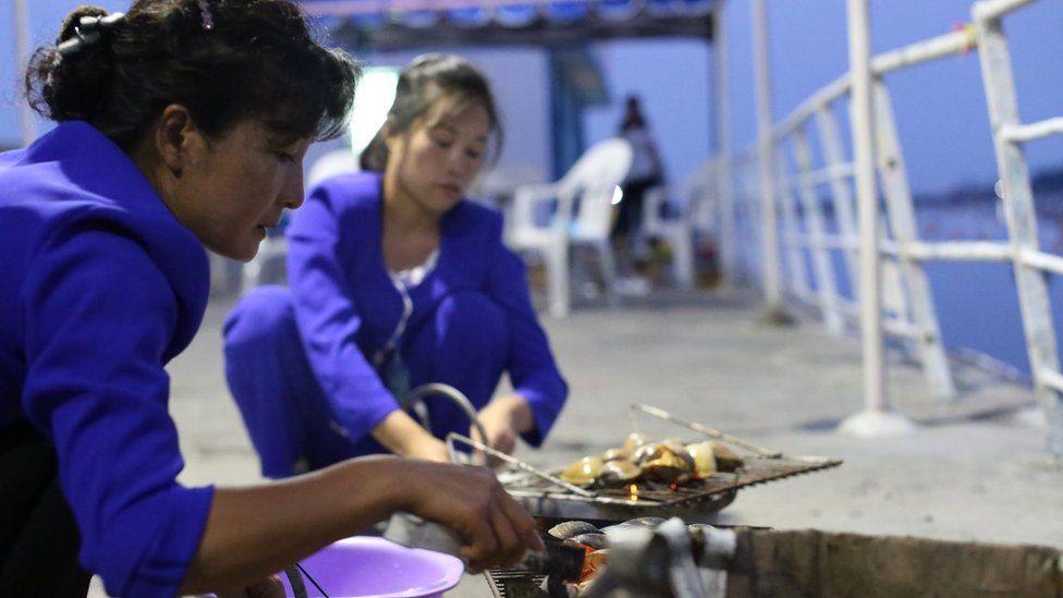 Two women grilling clams