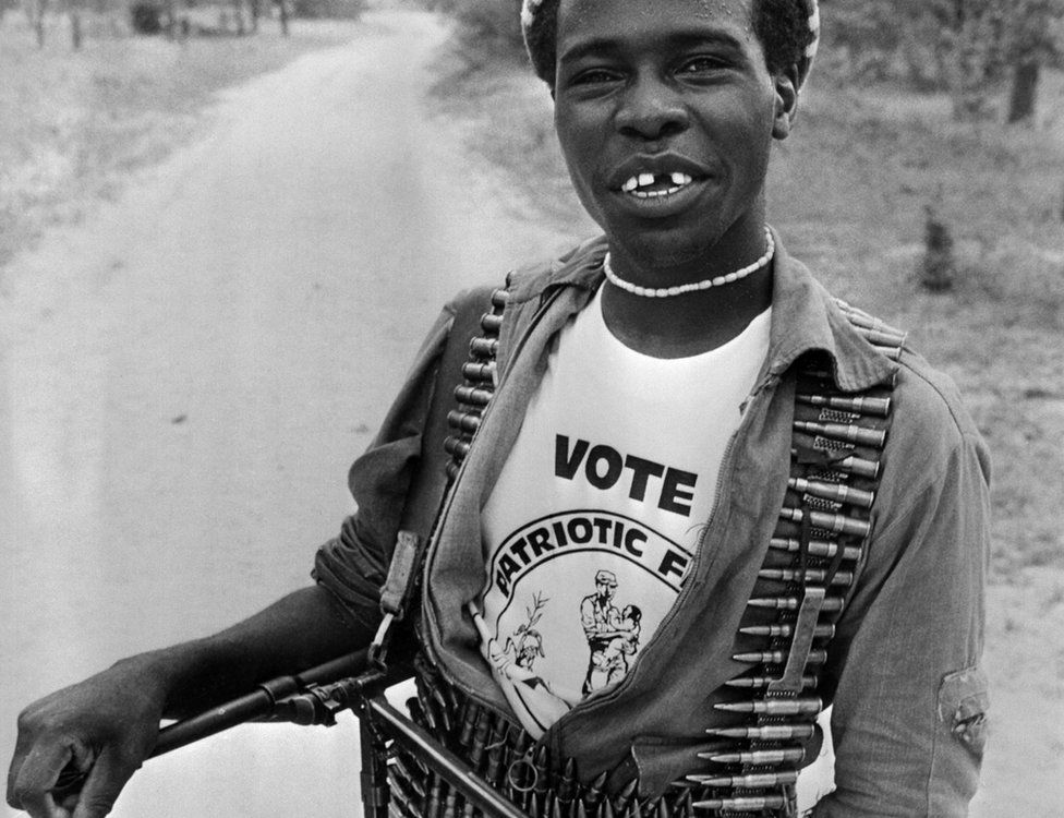 A fighter who supports the Patriotic Front carrying bullets and a machine gun, smiles during the general elections, March 04, 1980 in Lupane camp