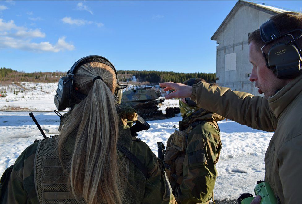 Ole Vidar points in the distance as he speaks with two soldiers