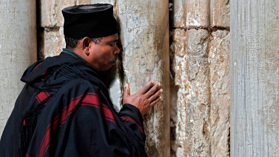 A Christian Ethiopian priest prays next to the closed door of the main entrance of the Church of the Holy Sepulchre in the Old City of Jerusalem on February 26, 2018 after Christian leaders took the rare step of closing the church, seen as the holiest site in Christianity, the previous day at noon