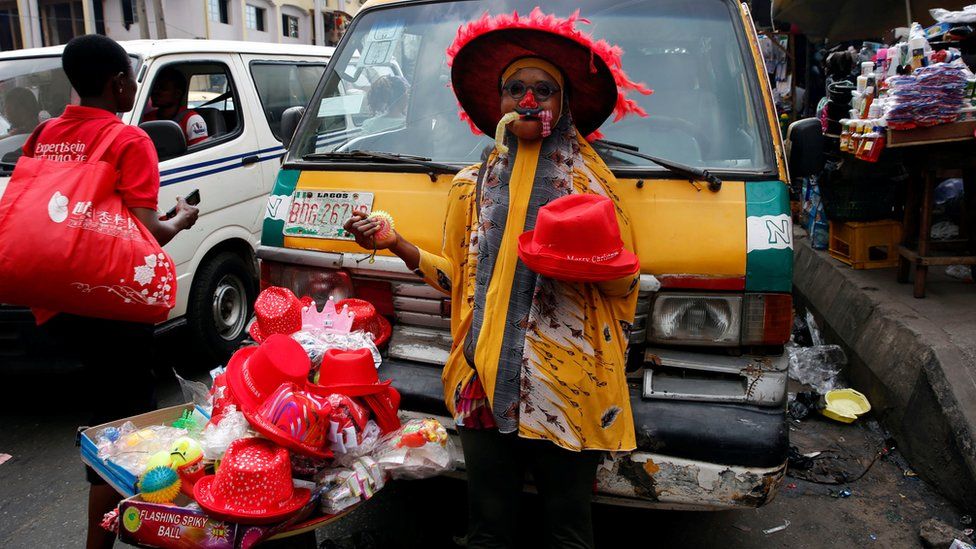 A woman sells Christmas items in front of a vehicle parked along a road in the central business district, near Marina in Lagos, Nigeria December 13, 2016