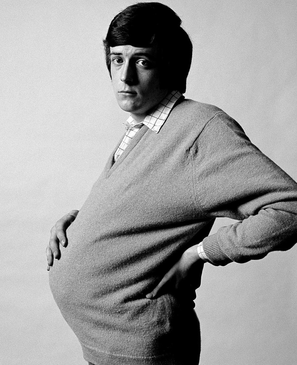 Photograph of a man holding his pregnant stomach for an advertising campaign designed to promote the use of contraceptive. Photograph by Alan Brooking taken in 1970 (The Pregnant Man).