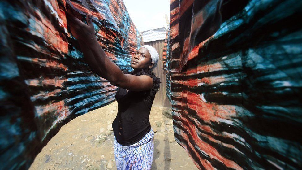 A woman hangs dyed textiles in Adjame, Abidjan, Ivory Coast, 22 January 2018.