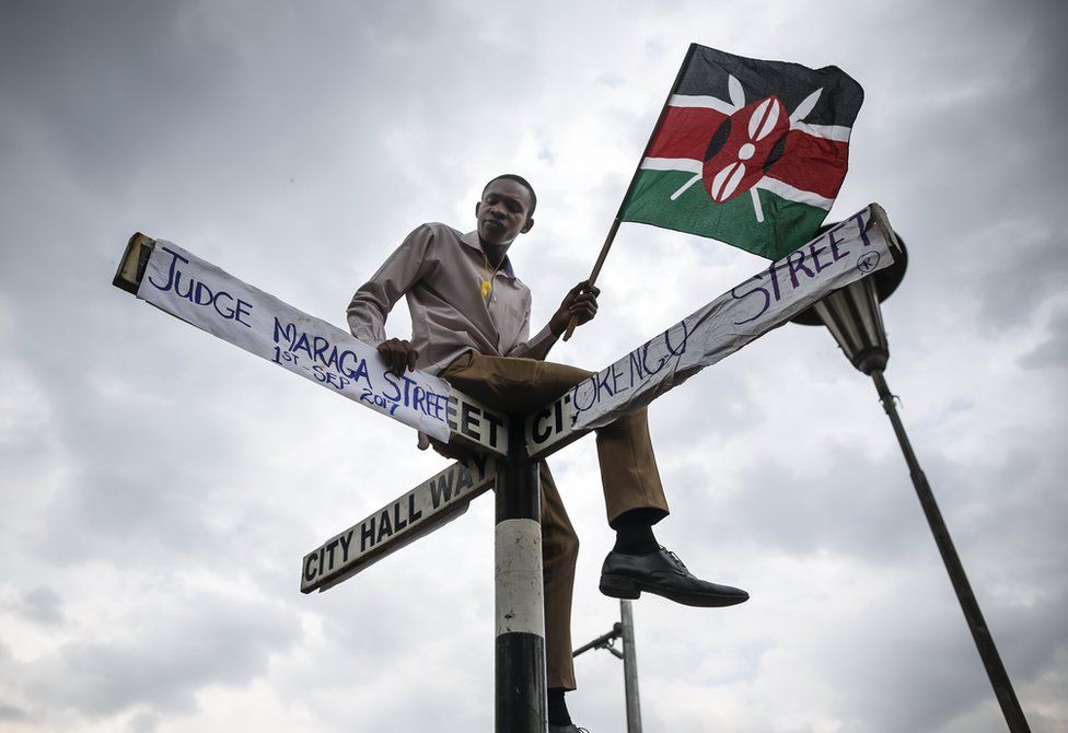 A supporter of The National Super Alliance (NASA) opposition coalition and its presidential candidate Raila Odinga sits on top of a street sign post that has been relabeled "Judge Maraga Street", referring to Chief Justice David Maraga, and "Orengo Street", referring to NASA"s lawyer James Orengo, in front of the Supreme Court in central Nairobi, Kenya, 01 September 2017. Kenya"s Supreme Court on 01 September overturned the re-election of President Uhuru Kenyatta and ordered a re-run of the election within 60 days, citing irregularities. Ecstatic opposition supporters marched through the city to celebrate "historic" court decision.
