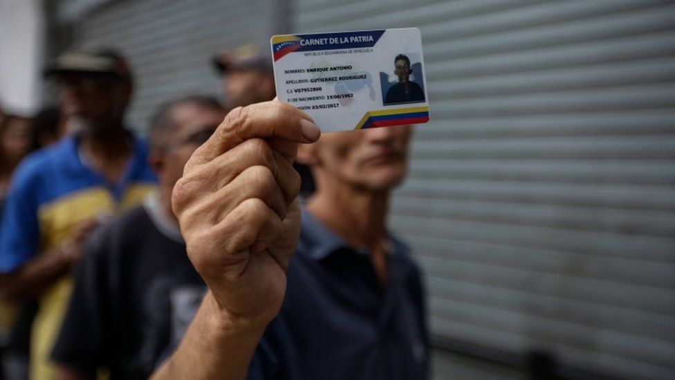Un venezolano muestra su documento de identidad mientras espera para votar.