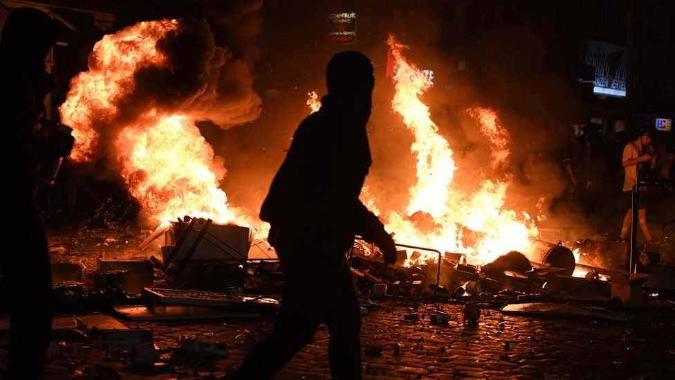 Demonstrators walk in the street while a fire burns in the middle of town during an anti-G20 protest on July 7, 2017 in Hamburg, Germany