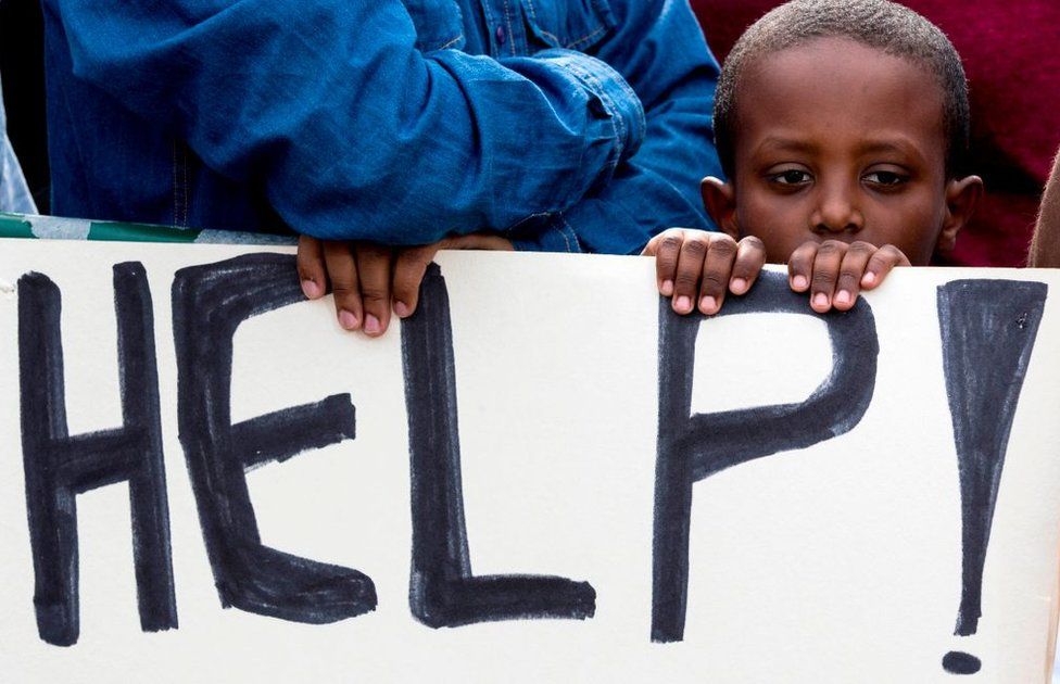 An African child stands behind a sign during a demonstration outside the Embassy of Rwanda in the Israeli city of Herzliya on February 7, 2018, against the Israeli government's policy to forcibly deport African refugees and asylum seekers to Rwanda and Uganda. Israel began on January 3 implementing a plan to deport by April tens of thousands of African migrants, mainly Eritreans and Sudanese, who entered the country illegally, threatening to arrest those who stay. Israel tacitly recognises that the Sudanese and Eritreans cannot be returned to their dangerous homelands, so it has signed deals with Rwanda and Uganda, which agree to accept departing migrants on condition they consent to the arrangement, activists say.