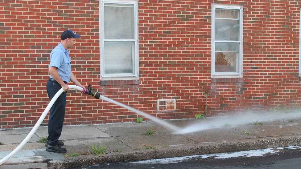 A Baltimore firefighter washes blood off of the sidewalk