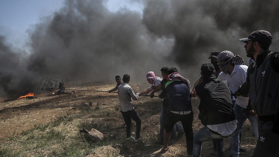 Palestinians protesters pulling barbed wire fence installed by Israeli army along the border during clashes after protests near the border with Israel in the east of Gaza Strip