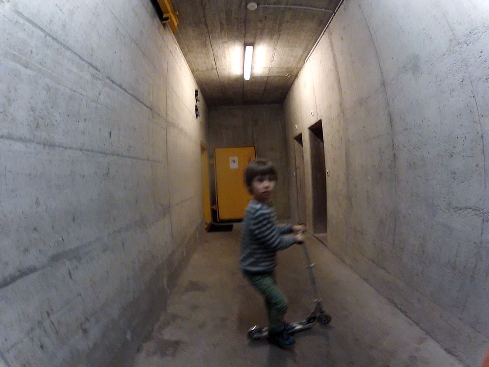 Каспер катается на самокате по коридорам миграционного центра, бывшего бомбоубежища. Март 2016 года, Швейцария