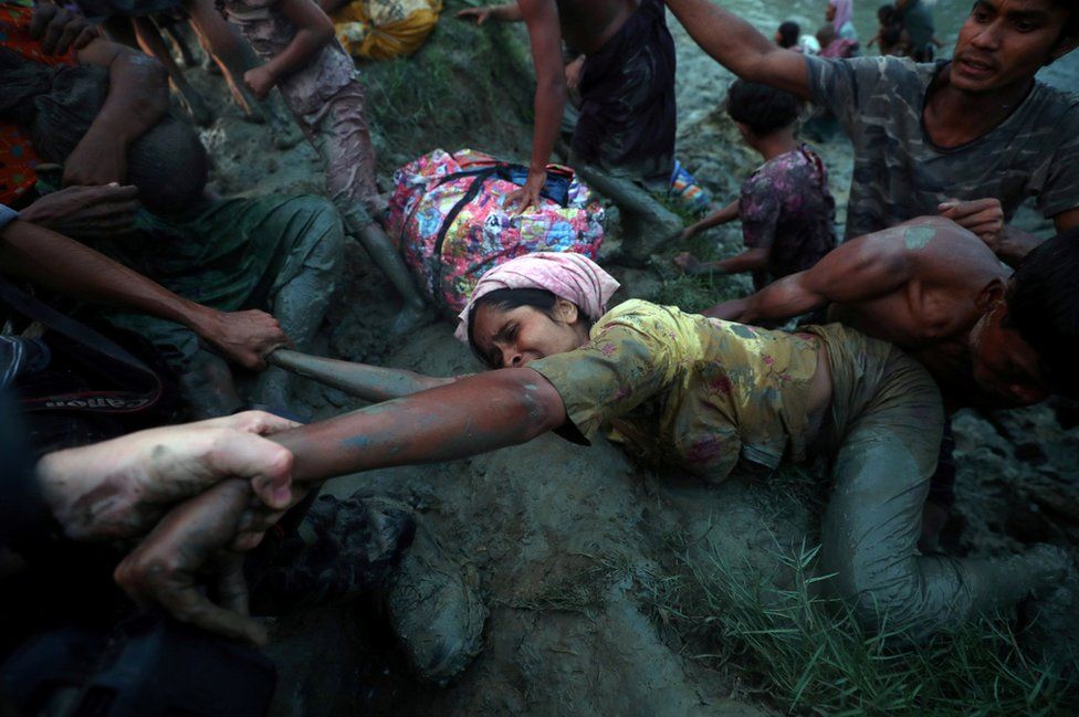 Fotógrafos ajudam uma mulher rohingya no rio Naf.