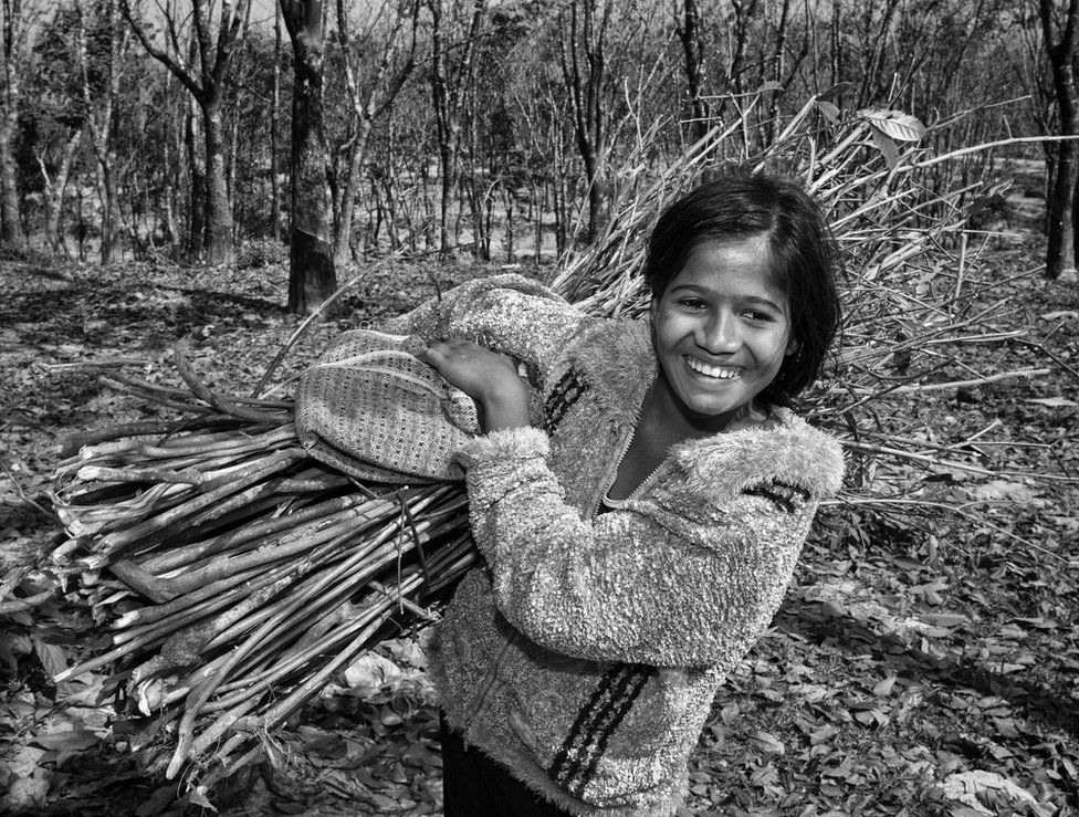 A girl carries a bundle of sticks