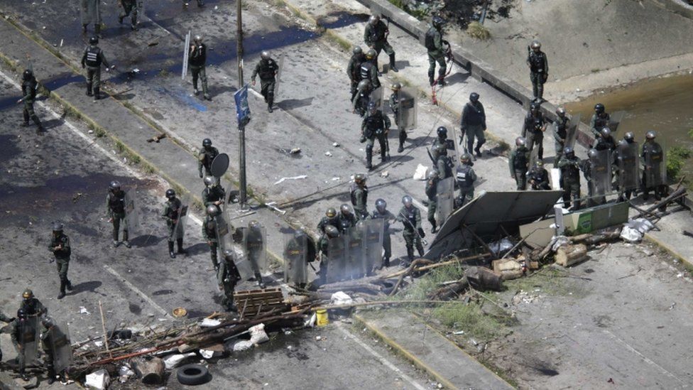 Miembros de la policía venezolana se refugian detrás de una barricada en Caracas.