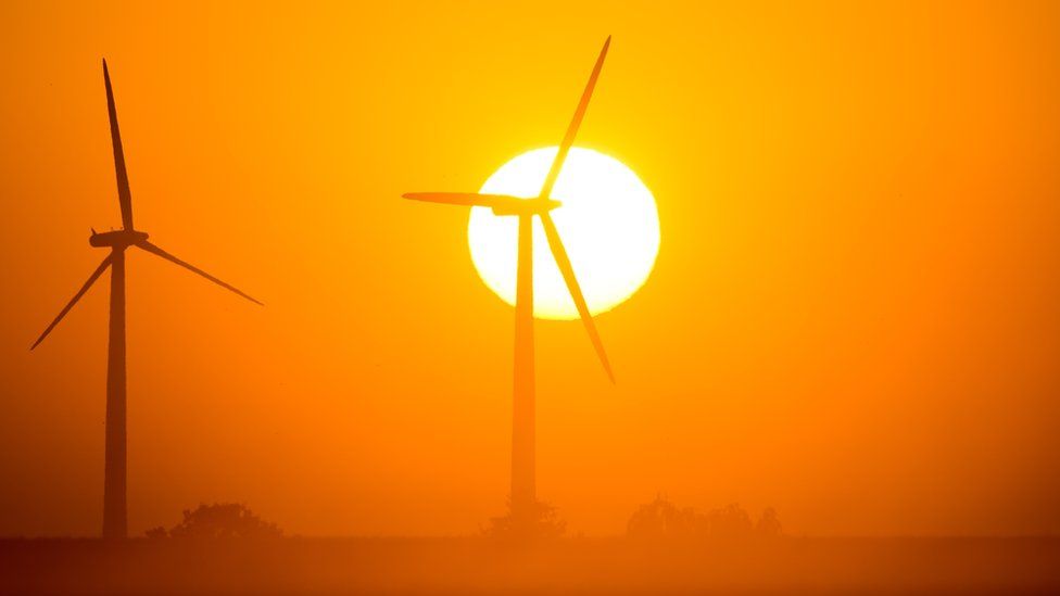 The sun rises behind wind turbines in Mallnow, eastern Germany on August 20, 2015.