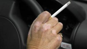 Adulto fumando en carro