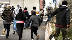 inmigrantes corriendo tras un camión que se dirige al Eurotúnel en Calais, Francia