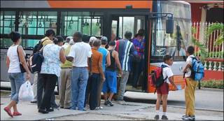 Cubanos haciendo fila para subir a un autobús