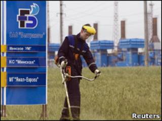 Мужчина стрижет траву у газокомпрессорной станции в Белоруссии