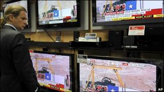 Cliente de loja de eletrodomésticos em frente a TVs ligadas no caso do Chile