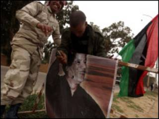 Rebeldes que partiram de cidade atacada violam imagem de Khadafi no caminho rumo a Benghazi