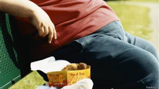 Persona obesa comiendo comida rápida.