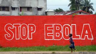 Niña pasea frente a un graffiti contra el ébola