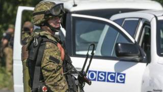 Пророссийский сепаратист наблюдает за автомобилем миссии ОБСЕ