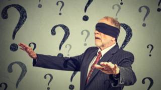 Un hombre con los ojos vendados camina entre signos de interrogación