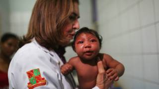 Un guardia sostiene un panfleto que alerta sobre el virus zika