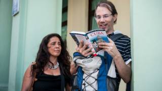 Una pareja de turistas estadounidenses miran un libro de viajes sobre Cuba en La Habana