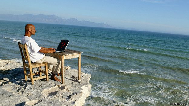 Hombre con una computadora frente al mar
