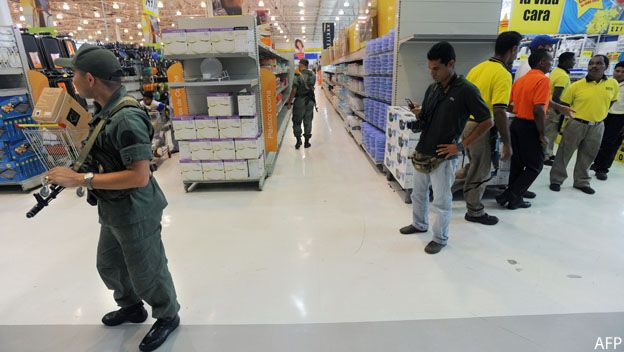 Guardias vigilan en las gondolas de supermercado venezolano semi vacías por la escasez de productos.