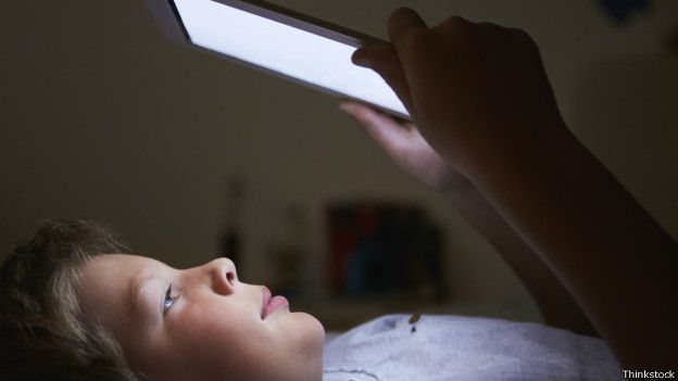 Niño leyendo un libro electrónico en la oscuridad