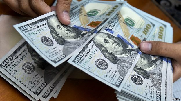 Un cajero cuenta billetes de 100 dólares