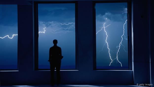 Una persona mira una tormenta en la ventana