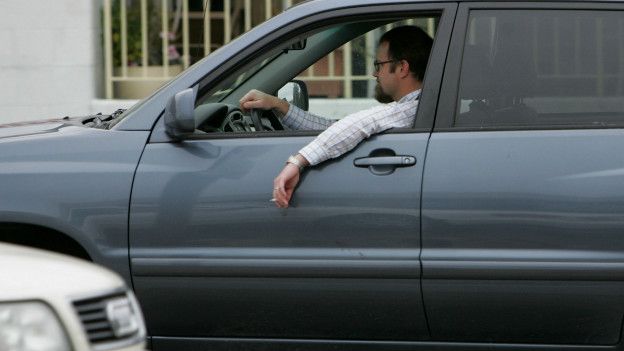 Conductor fumando en carro con la ventana bajada