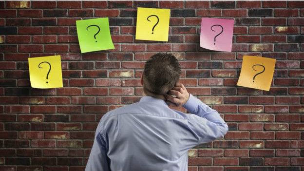 Una persona frente a varios signos de interrogación