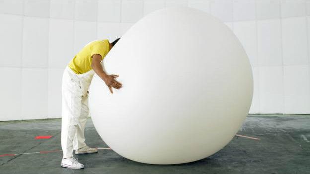 Una persona hundiendo la cabeza en una pelota inflable gigante
