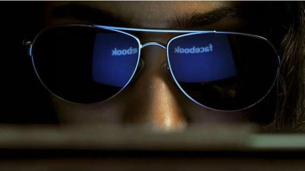 Logo de Facebook reflejado en los lentes de una mujer