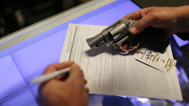 Un ciudadano llena una planilla durante una venta de armas.
